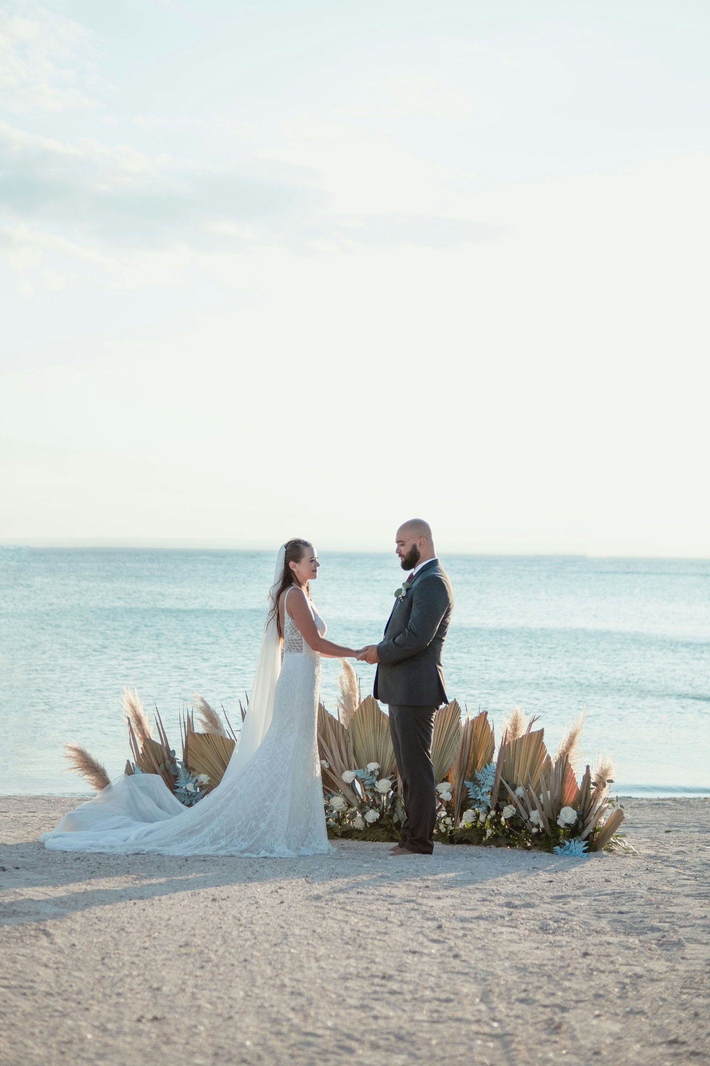 Newlyweds holding hands at a beachside ceremony.